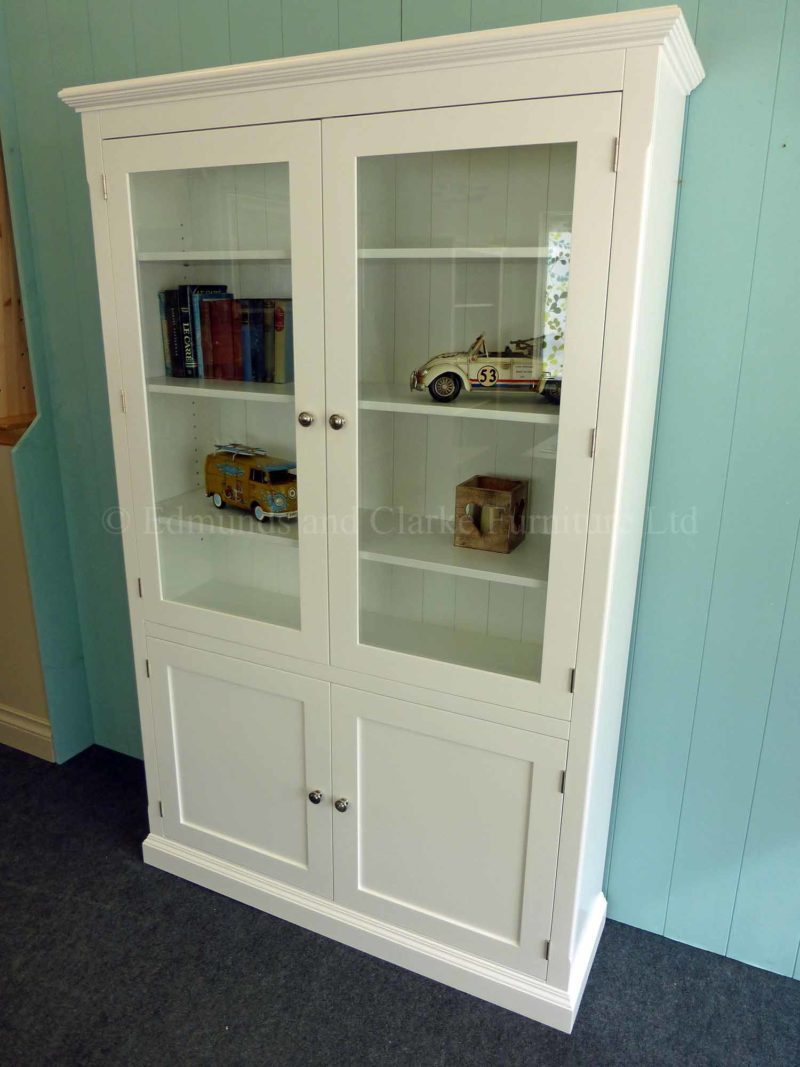 Edmunds Painted Glazed/Panelled Bookcase. Adjustable shelves with glazed top and cupboard below. Image is colour white and painted white. Different finishes available and different knob opt