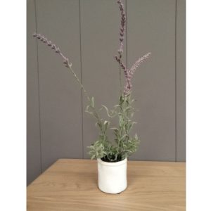 Small faux lavender plant with four purple sprigs in a white ceramic pot on a wooden table